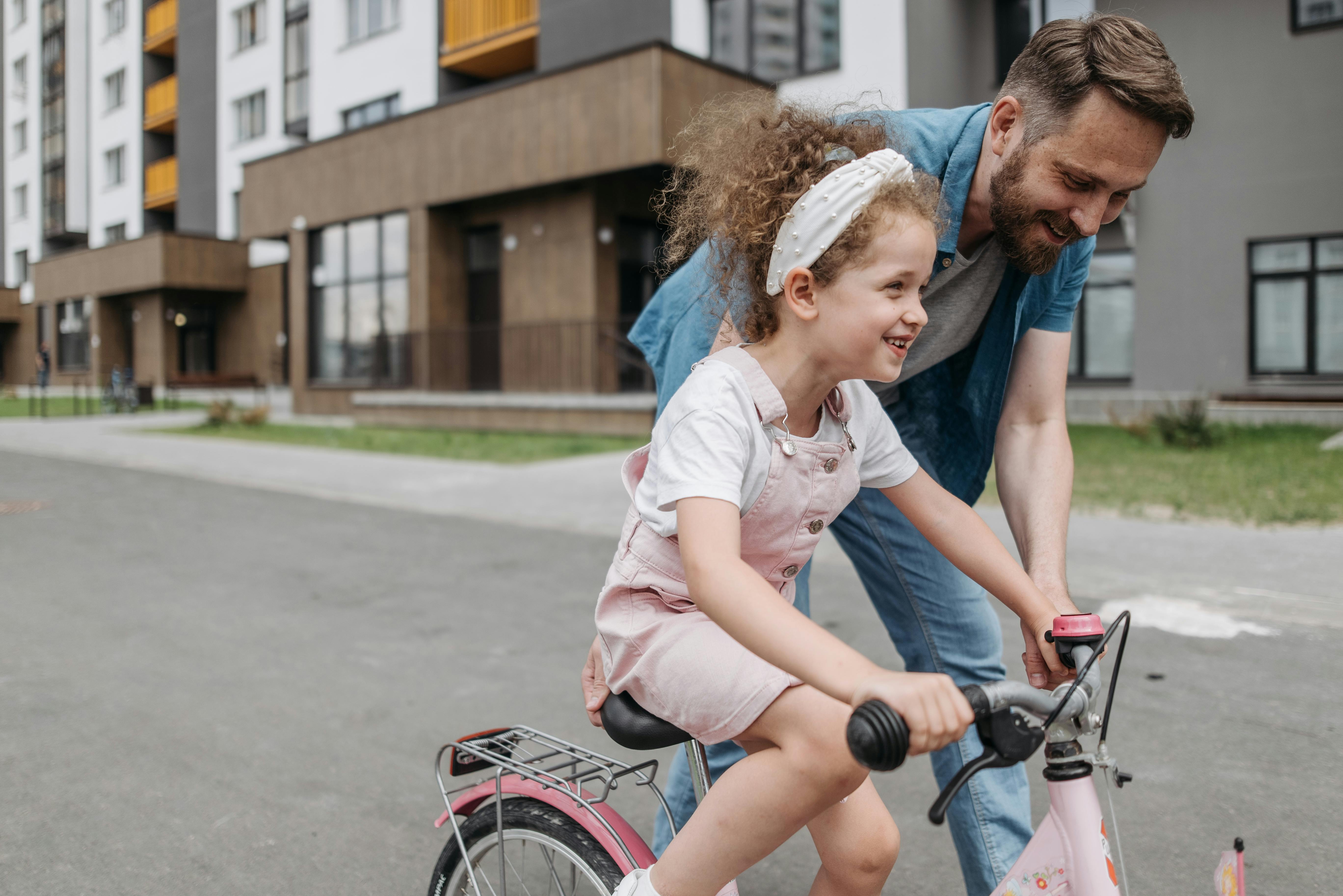 Girl Learning How to Ride a Bicycle with her Dad · Free Stock Photo