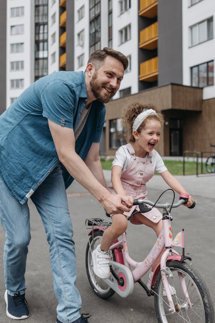 Man Pushing Girl On A Bicycle