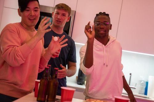 Free Group of friends playing a drinking game indoors, enjoying a lively party atmosphere. Stock Photo