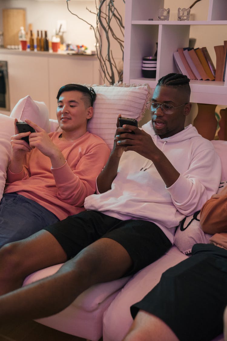 Men Sitting On The Couch And Playing Games On A Retro Console 