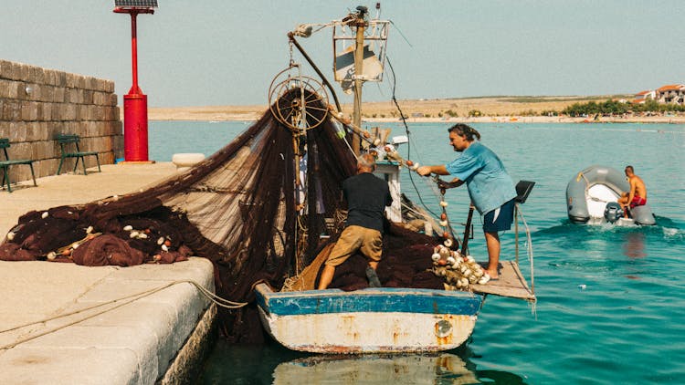 Fishermen Pulling The Fishing Net Into The Boat