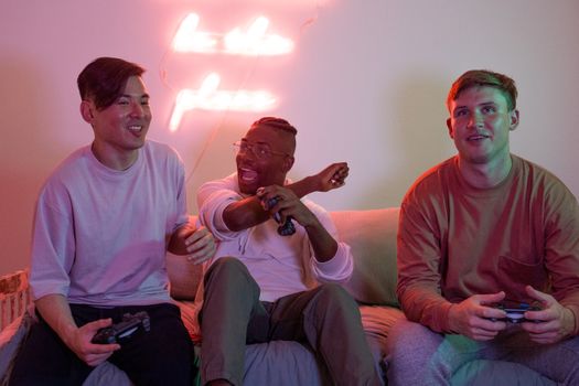 Three friends enjoying a fun gaming session indoors with neon decor.