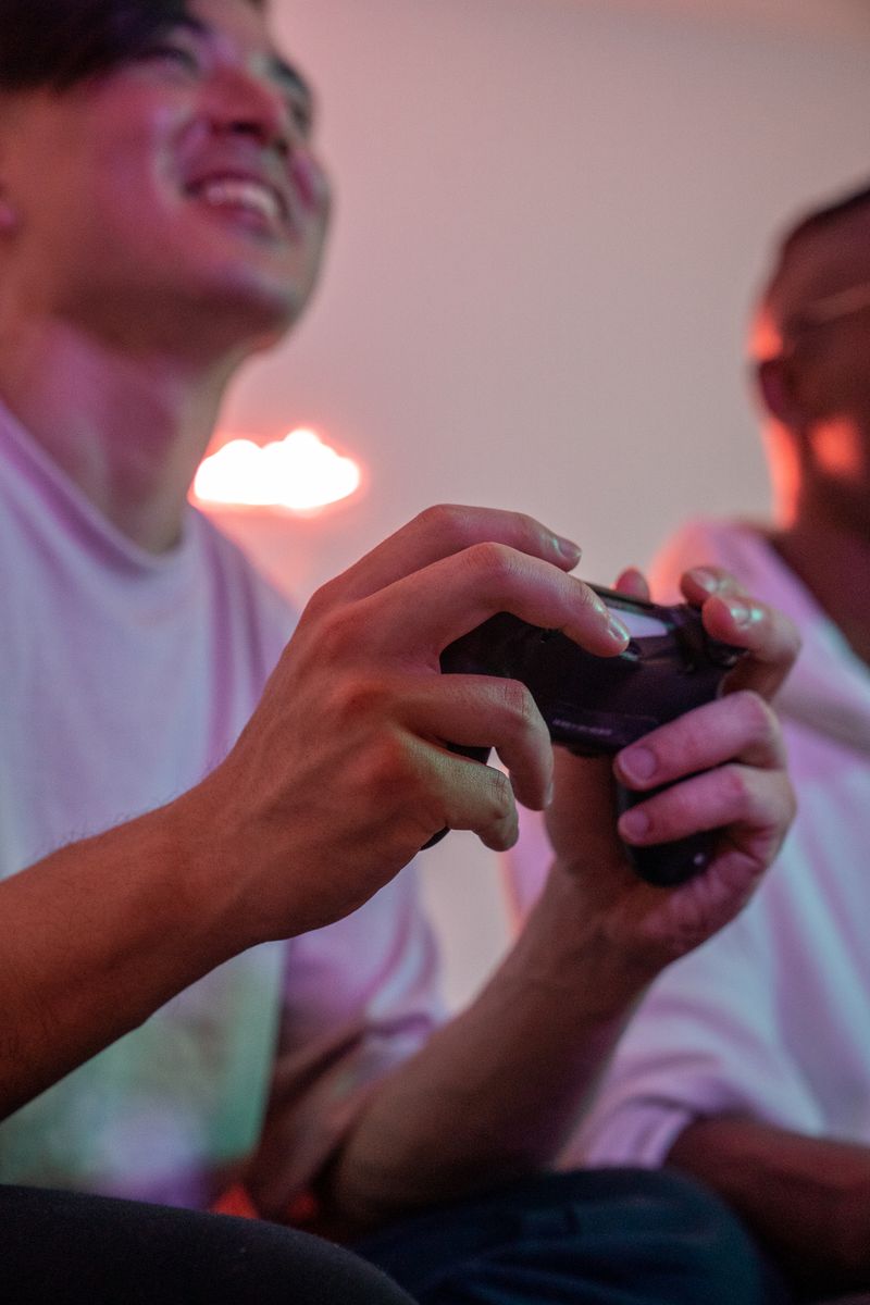 Close-up of two adults playing video games indoors, holding a joystick and smiling.