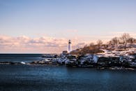 冬日里，缅因州多石海岸线上灯塔的景色在明亮的天空下如画般美丽