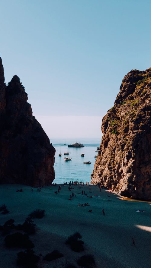 Free Majestic rock formations framing a serene beach and sea at La Calobra in Mallorca, Spain. Stock Photo