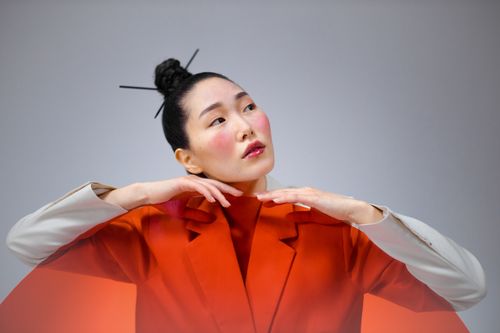 Free Studio portrait of a woman in a stylish red suit with hair bun and contemplative expression. Stock Photo