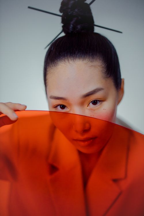 Free A stylish studio portrait of a woman posing with an orange filter, conveying elegance and modernity. Stock Photo