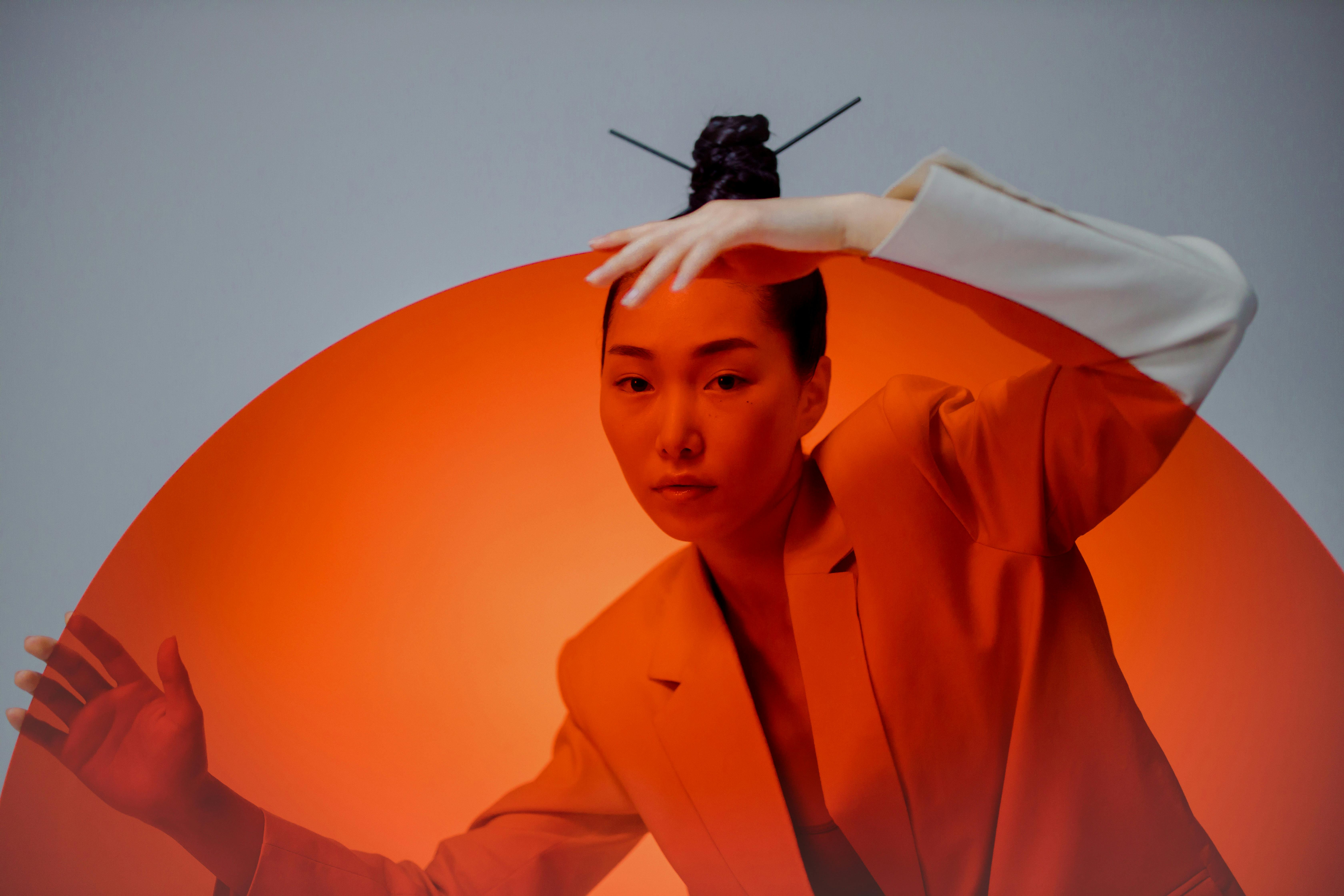 a woman in coat behind the red round transparent glass