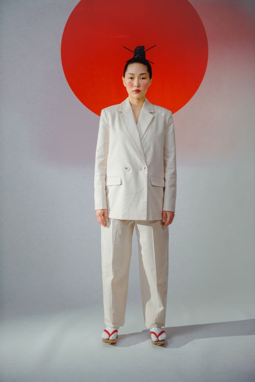 Free Asian woman standing in formal attire against a minimalist backdrop with a red circle. Stock Photo