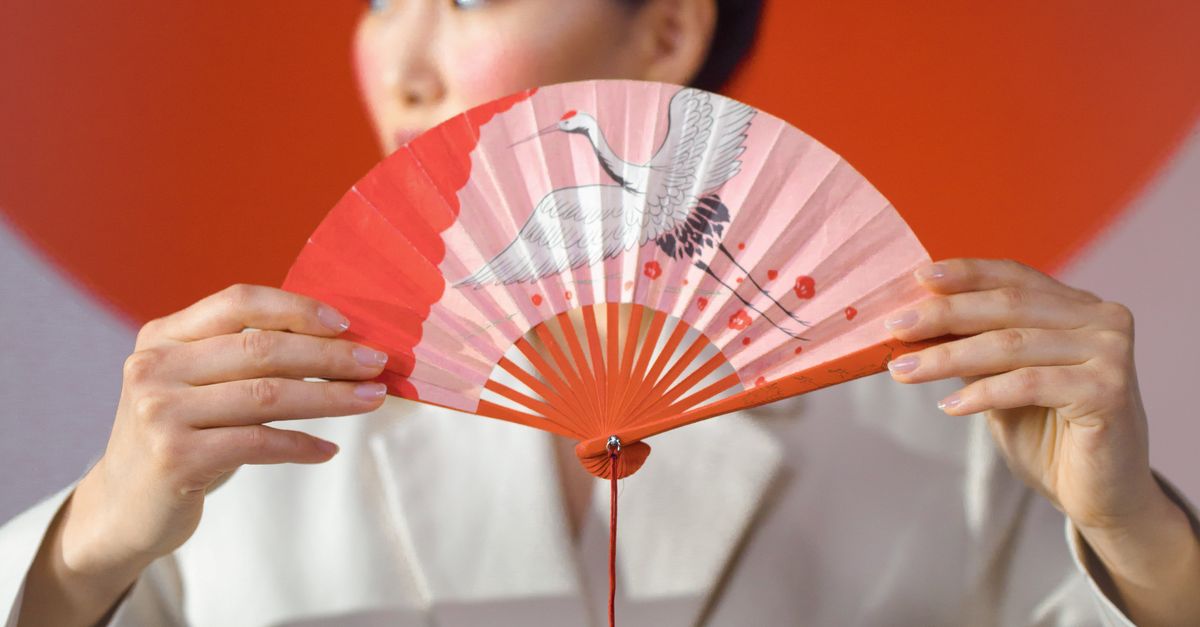 A Woman Holding a Hand Fan · Free Stock Photo