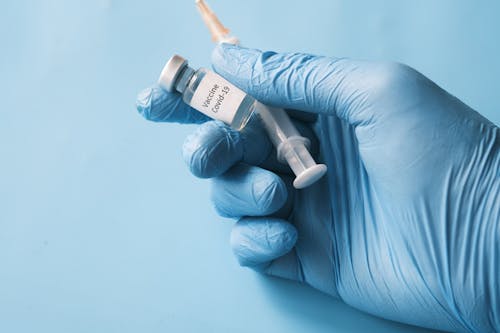 Free Person Holding A Vial Of Covid 19 Vaccine and Syringe Stock Photo