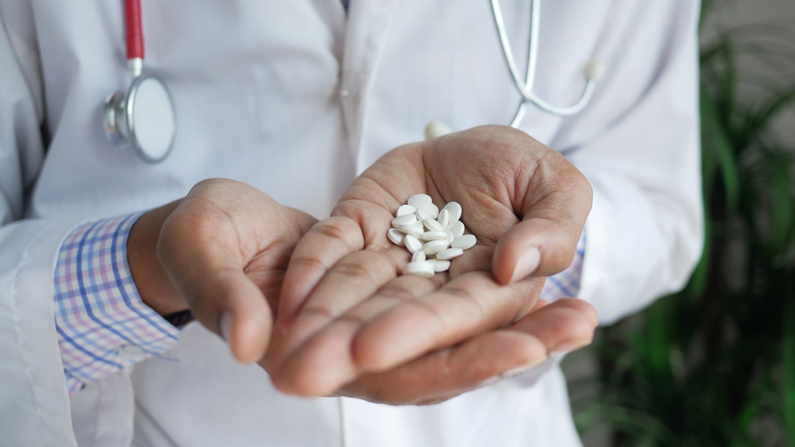 A close-up of a doctor holding white pills in their palms, emphasizing healthcare and medicine.