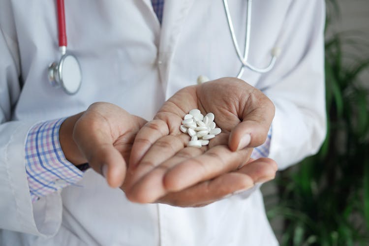 Person Holding White Pills