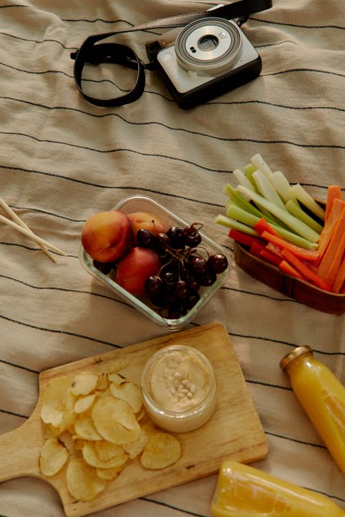 Free An inviting picnic setup with snacks, a camera, and fresh fruits and veggies. Stock Photo
