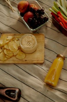 A casual picnic arrangement with chips, juice, fruits, and veggies, perfect for outdoor relaxation.