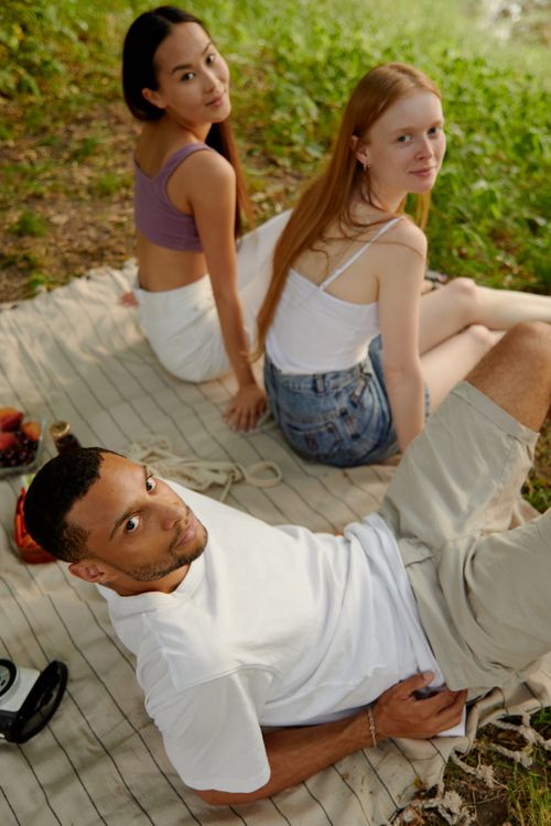 Free Three friends enjoying a relaxing outdoor picnic on a summer day. Stock Photo