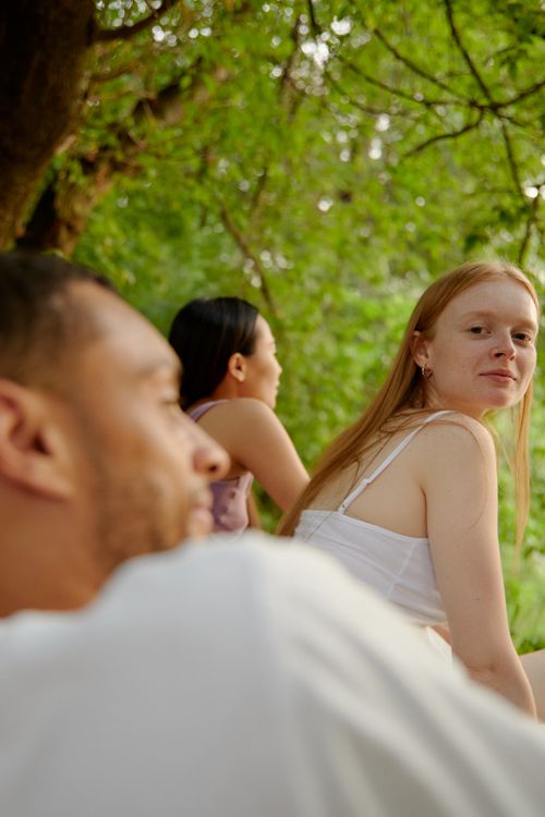 Free Three friends enjoying a peaceful day in a lush green park, symbolizing togetherness and leisure. Stock Photo