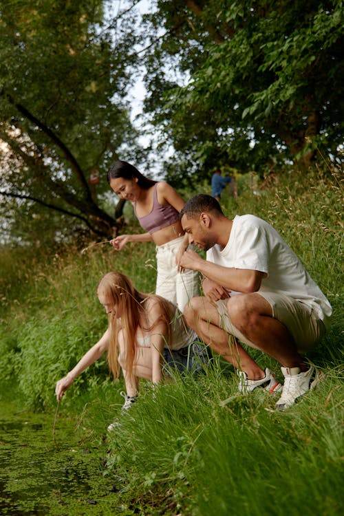 Free Man and Woman Crouching on Grass Beside a Woman Stock Photo