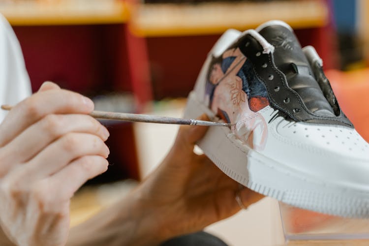 A Person Painting The White Sneaker 