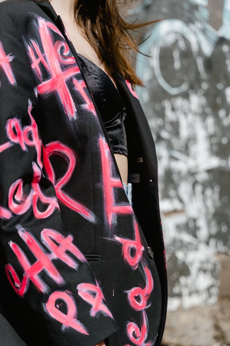 A Person Wearing Black Blazer With Pink Painted Letters