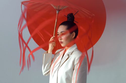 Free Artistic portrait of a woman holding a red umbrella, highlighting elegance and cultural aesthetics. Stock Photo