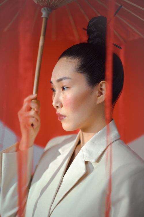 Free Elegant side view portrait of a woman with a paper umbrella, exuding grace and style. Stock Photo