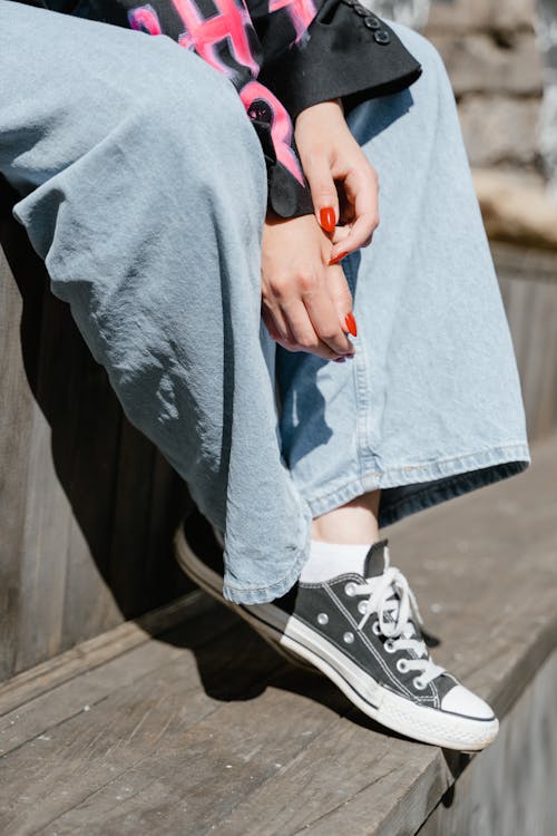 Person Wearing a Denim Pants and Black Converse Shoes · Free Stock Photo