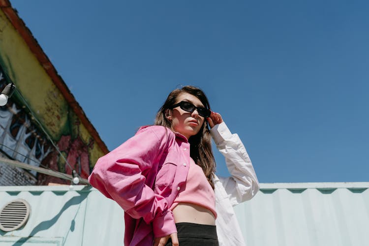 Woman In Pink Long Sleeves Touching The Sunglasses She Is Wearing