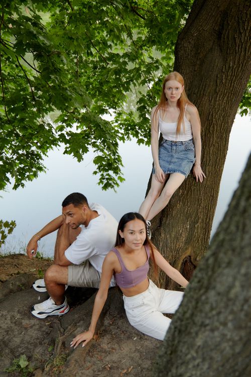 Free A diverse group of friends enjoying a calm moment outdoors under a tree, embodying modern street style. Stock Photo