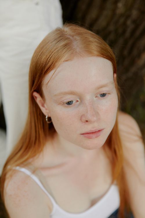 Free A thoughtful redheaded woman looking away in a serene outdoor setting. Stock Photo