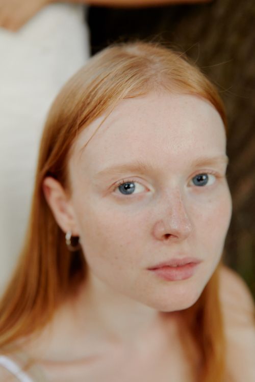 Free A captivating close-up portrait of a young red-haired woman with blue eyes. Stock Photo