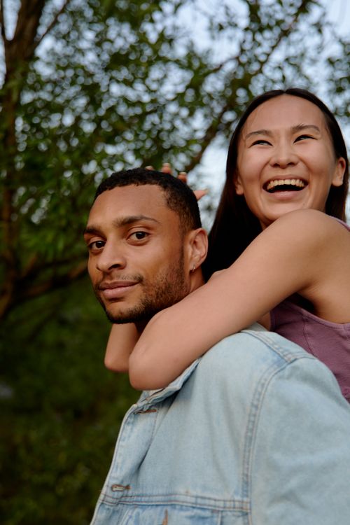 Free Happy couple enjoying a piggyback ride outdoors with laughter and joy. Stock Photo