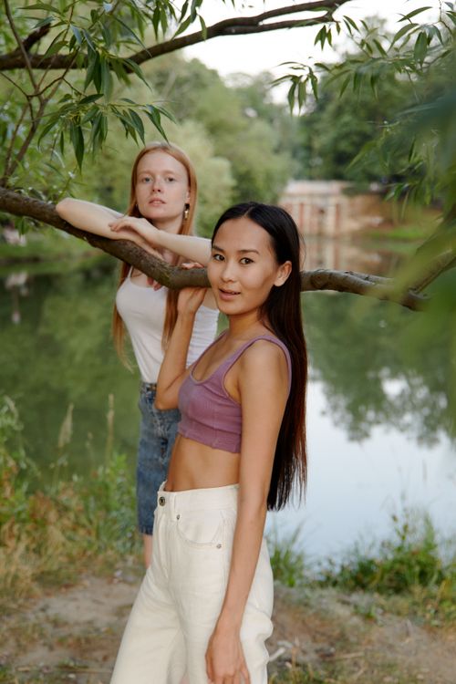 Free Two women enjoy a peaceful day by the lakeside, surrounded by lush greenery. Stock Photo