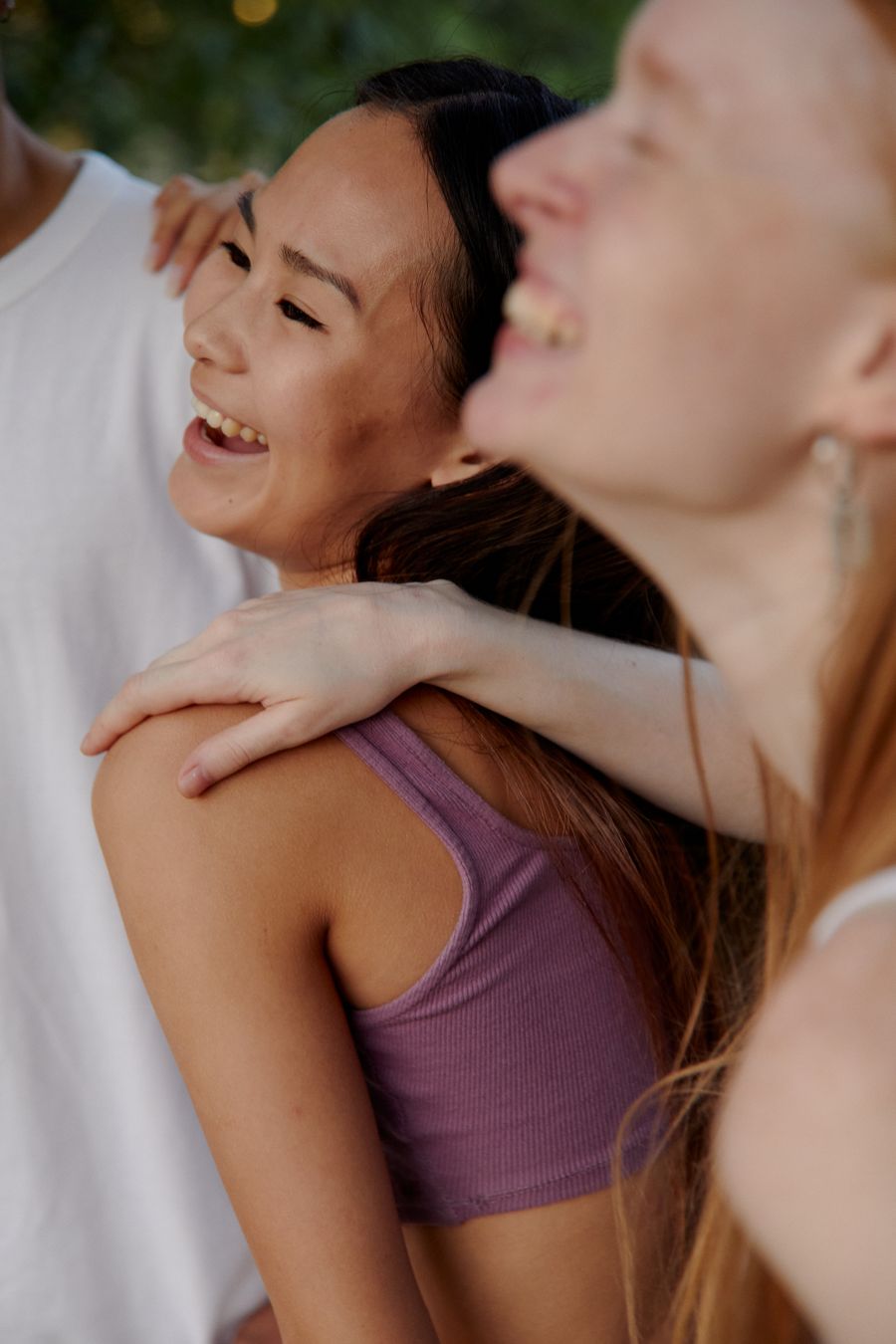 Sisters laughing with arms around each other outdoors
