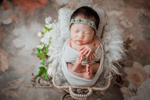 Free Peaceful newborn baby sleeping in a cozy basket, wrapped in soft white fabric. Stock Photo