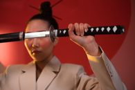 Man in White Suit Holding Black and Silver Sword