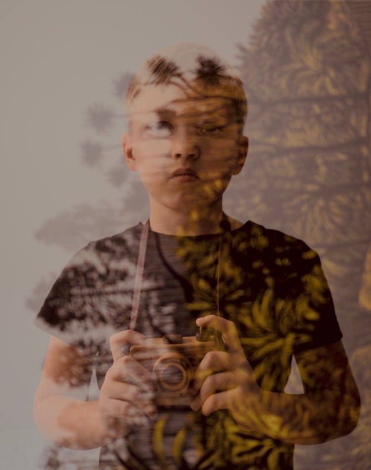 Boy Behind A Glass Holding A Camera