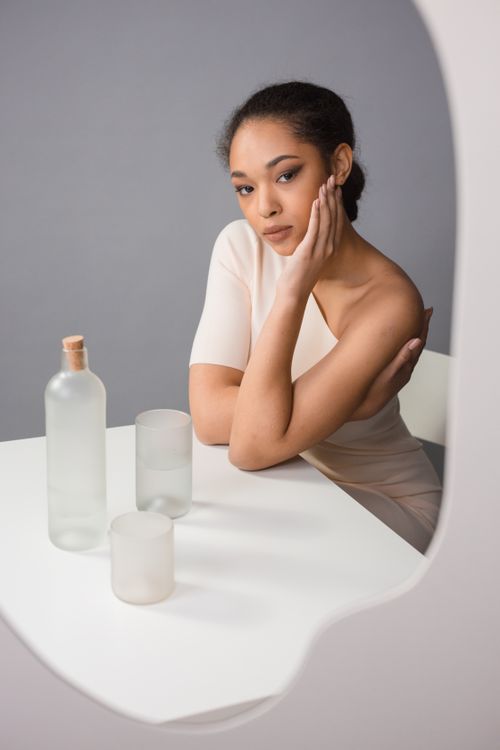 Free Portrait of a woman in studio, exuding grace in a minimalist setting with frosted glassware. Stock Photo