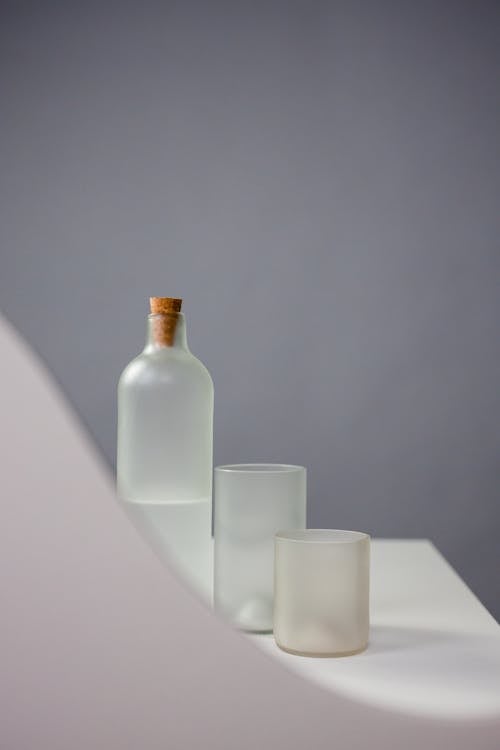 A Bottle with a Cork Cover beside Drinking Glasses