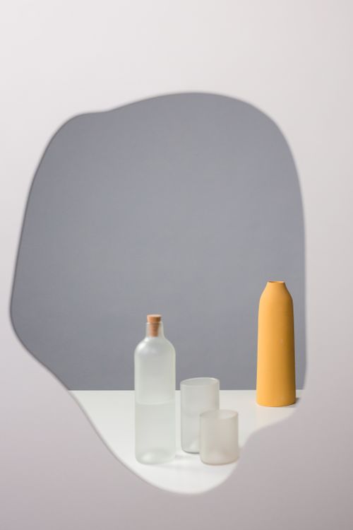 Free Artistic composition featuring bottles and abstract shapes against a neutral background. Stock Photo