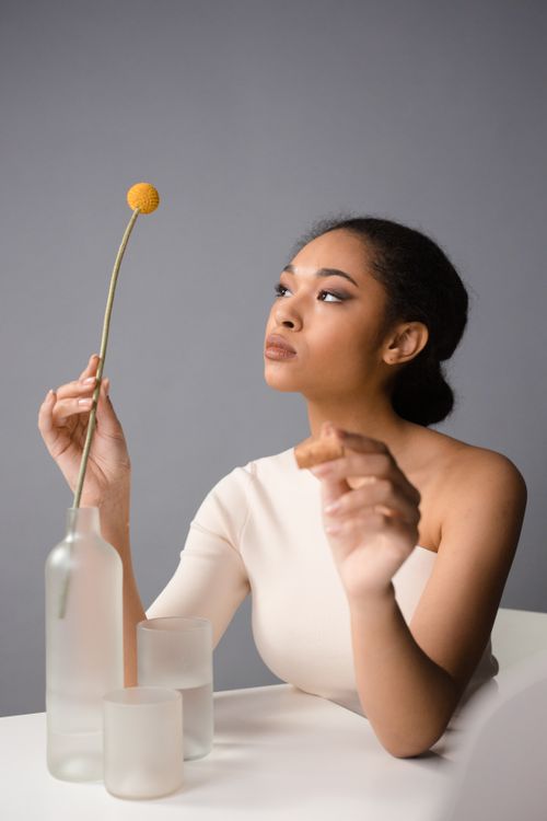 Free Elegant portrait of a woman in a minimalist setting with a single flower, highlighting grace and style. Stock Photo