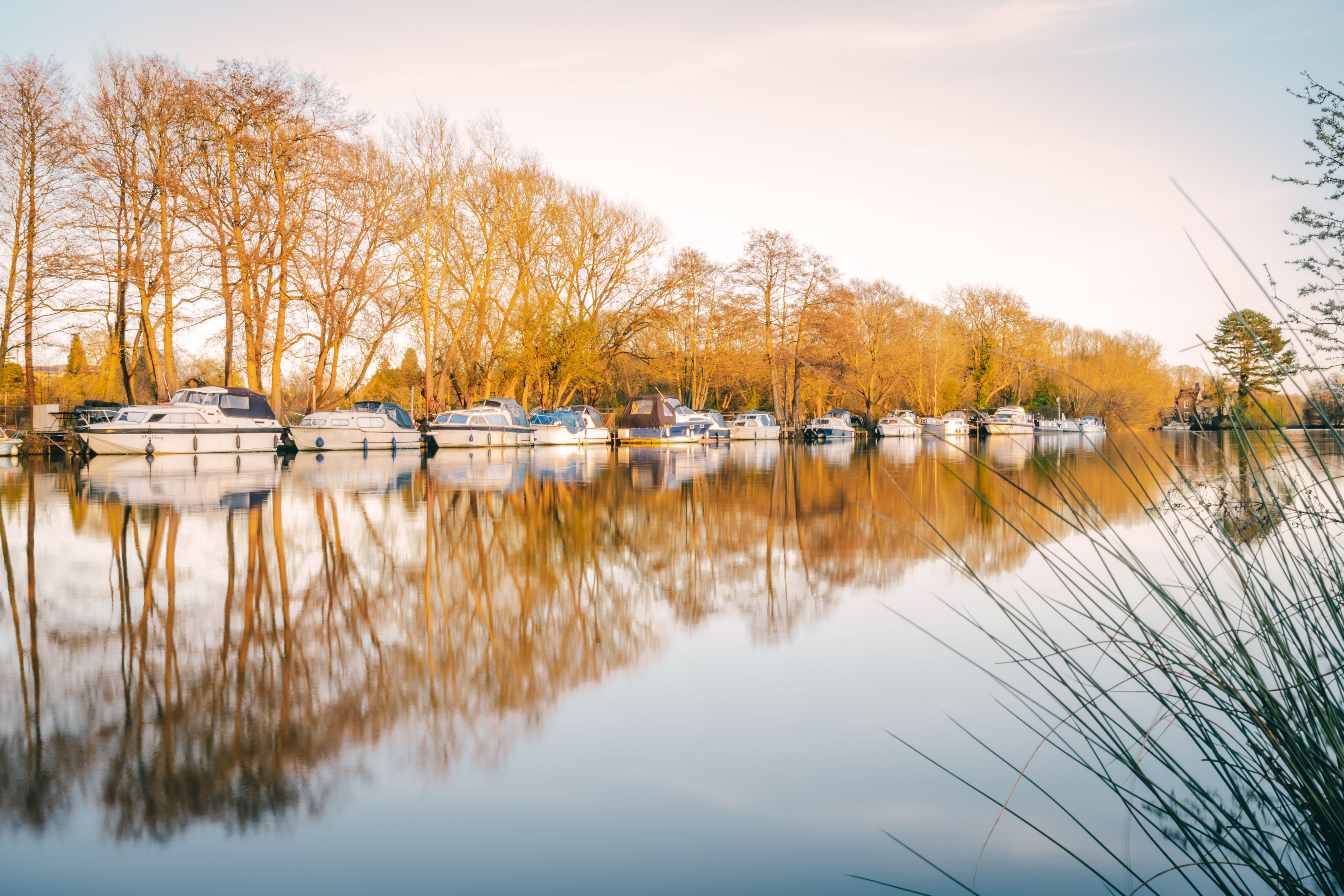 Tranquil morning scene at an Oxford river with docked boats and golden reflections.