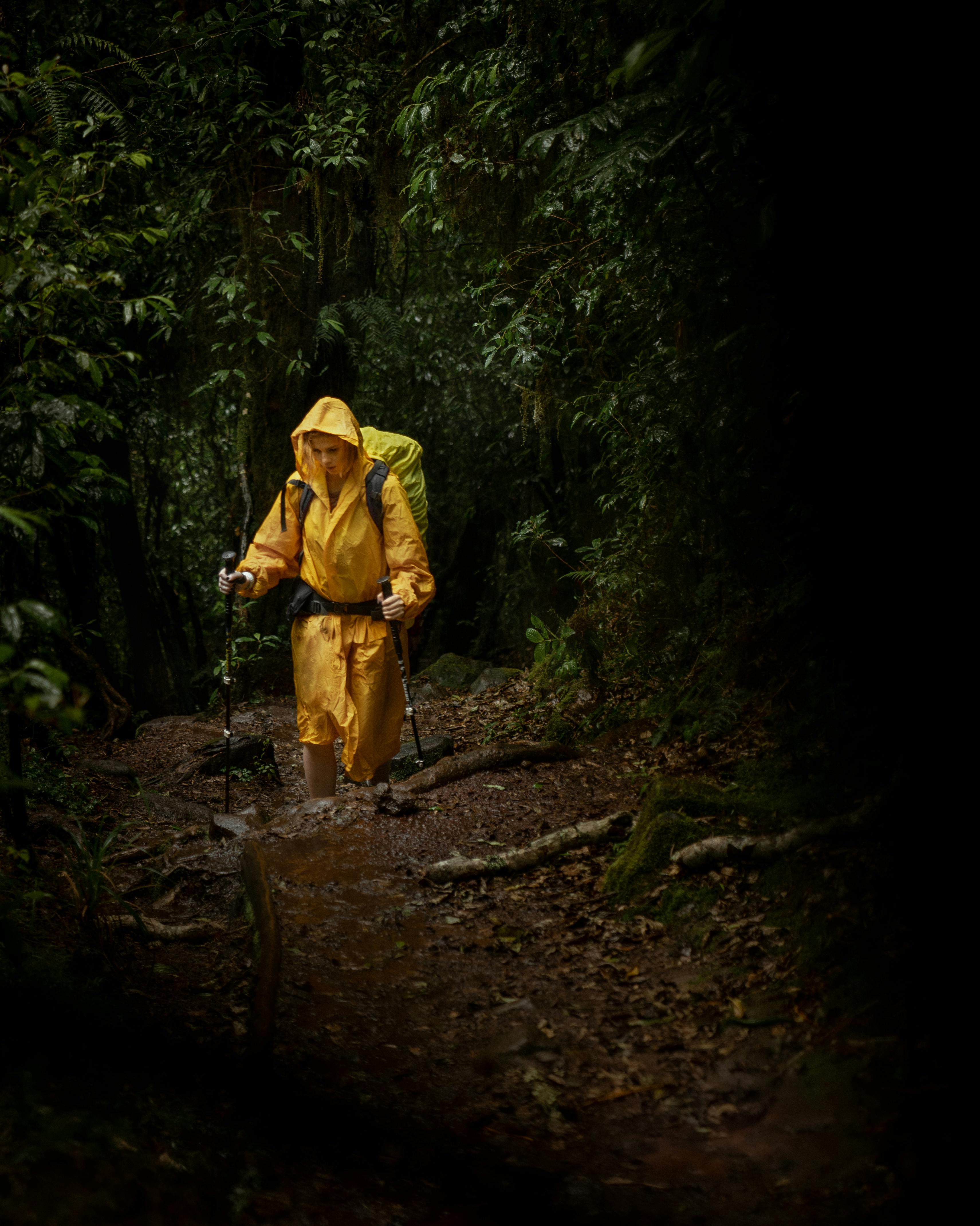 Hiker wearing bright waterproof shell on a wet forest trail in fall