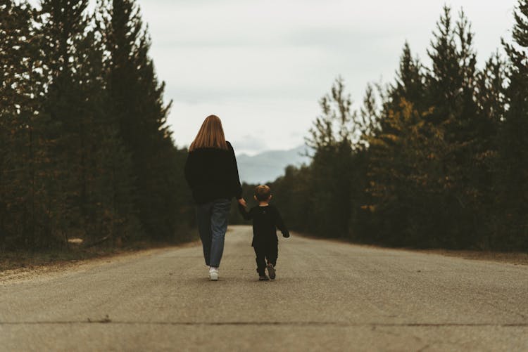 Mother And Child Holding Hands Walking On Path Road