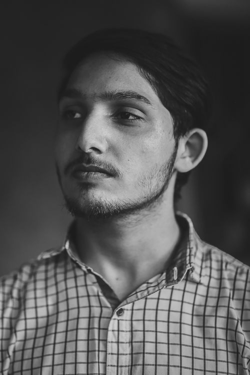 Free Grayscale portrait of a thoughtful young man with facial hair, wearing a checkered shirt in Lahore, Pakistan. Stock Photo