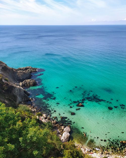 Free Stunning aerial view of a tranquil coastline with clear blue waters and rocky cliffs. Stock Photo
