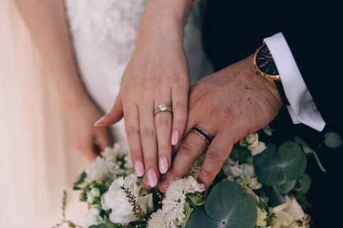 Free Close-up of newlywed couple's hands showing wedding rings over a beautiful flower bouquet. Stock Photo