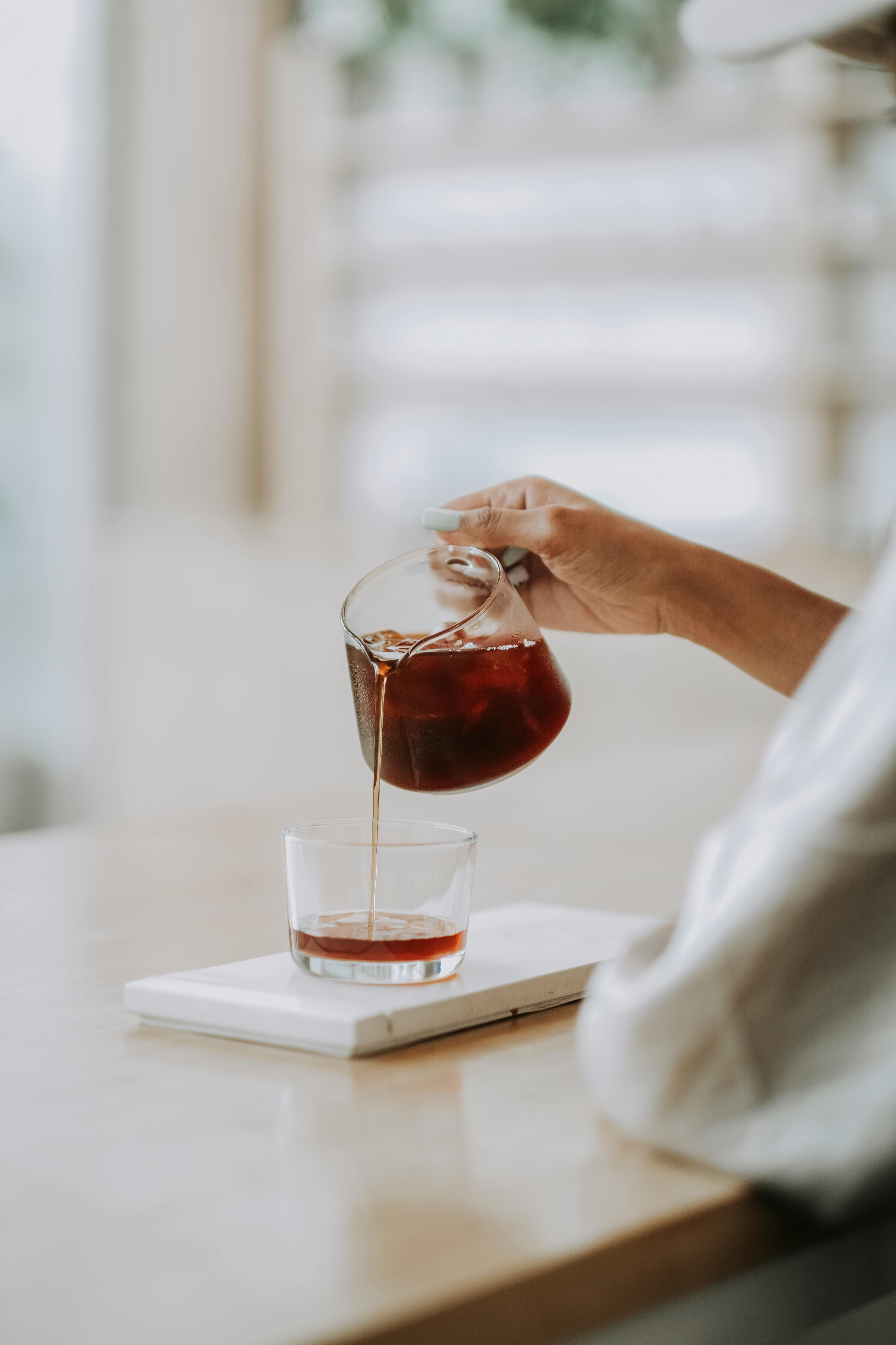 aesthetic shot of fresh coffee being poured into glass on a wooden counter in bali.