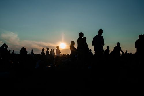 Free A group of people silhouetted against a vibrant sunset, capturing a serene moment outdoors. Stock Photo