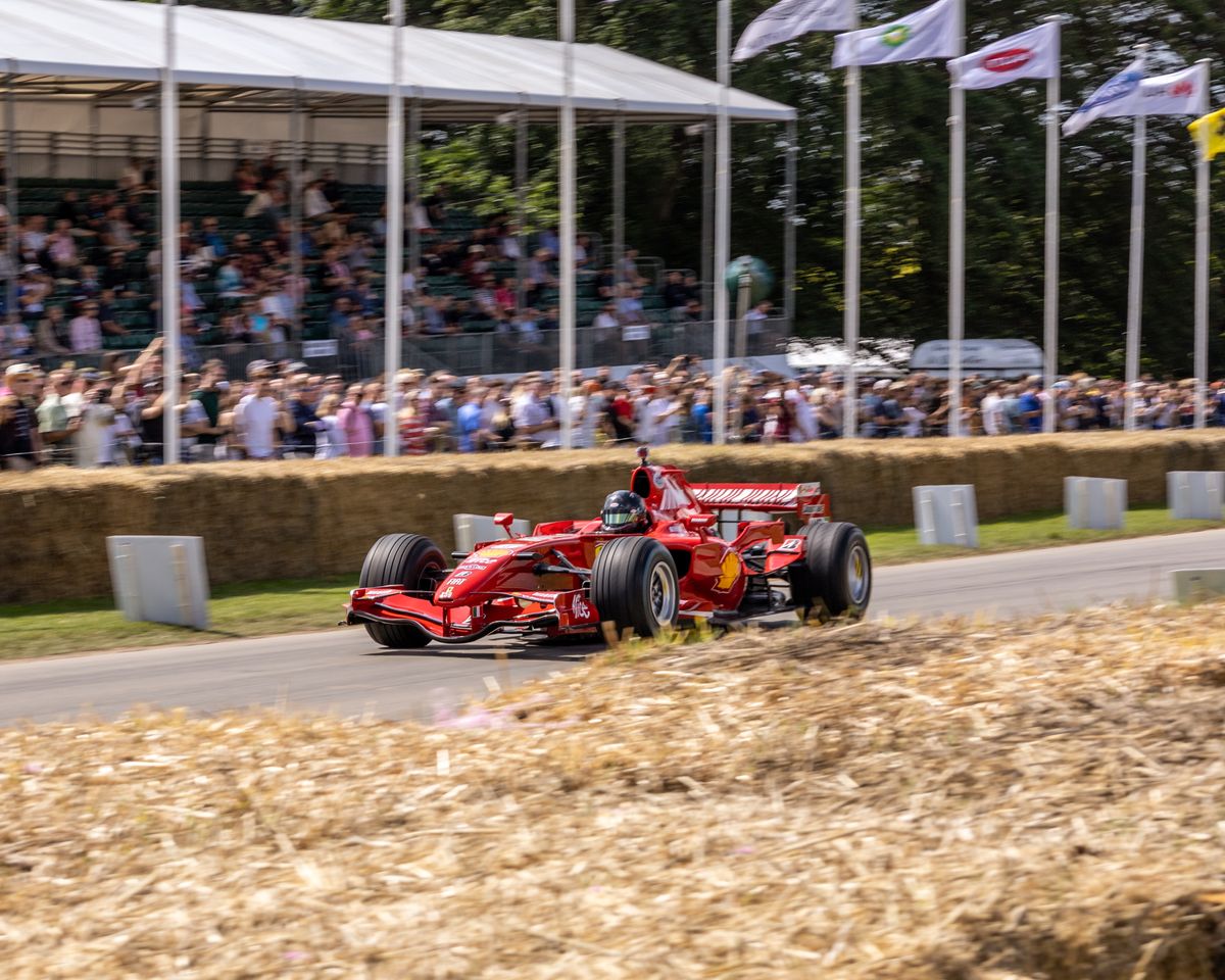 Monopost rosu de Formula 1 intre baloti de paie si tribune
